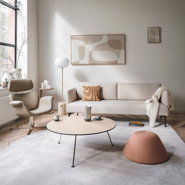 Neutral-toned living room featuring beige sofa, abstract art, light wood table, and terracotta accents in a cozy setting.
