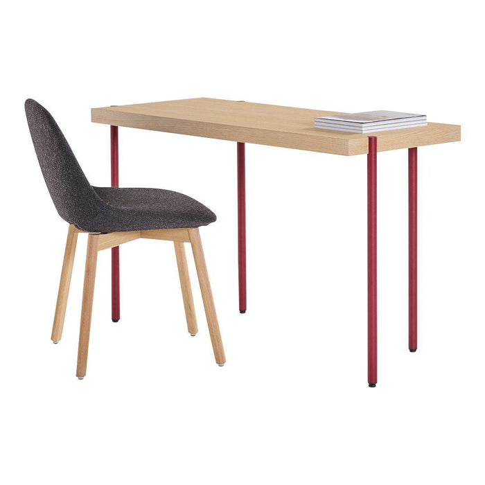 Light wood desk with red metal legs and a dark gray upholstered chair, featuring simple, modern lines and minimalistic design.