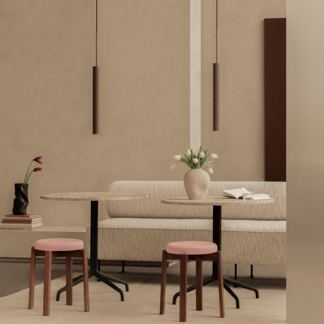 Neutral beige walls with soft pink stools, modern marble tabletop, and subtle brown accents create a serene dining space.