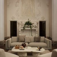 Beige striped sofa with soft gray cushions in a modern living room setting, complemented by a marble coffee table.