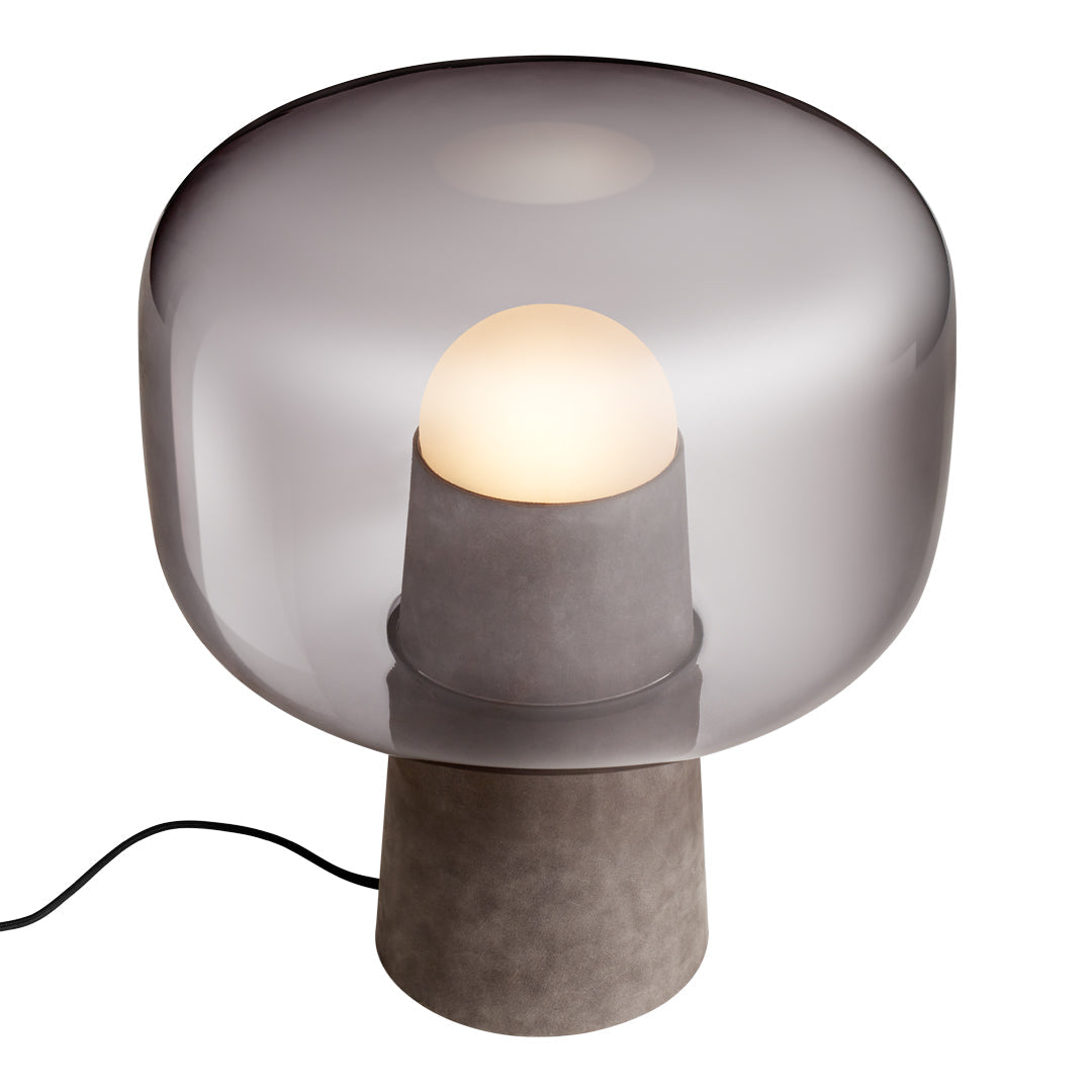 Gray glass table lamp with a smooth sphere shade and a matte concrete base, creating a modern, minimalist aesthetic.