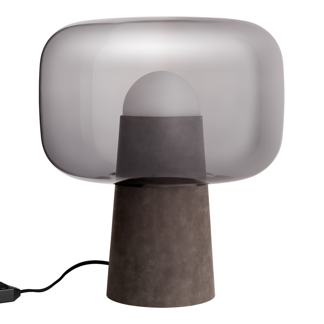 Grey-tinted glass shade lamp with a textured dark base, blending modern elegance with minimalist design.