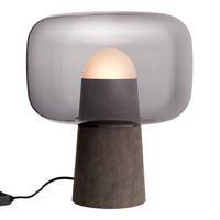 Modern table lamp with a smoky grey shade and a sleek black base. Round white bulb creates a soft, warm glow.