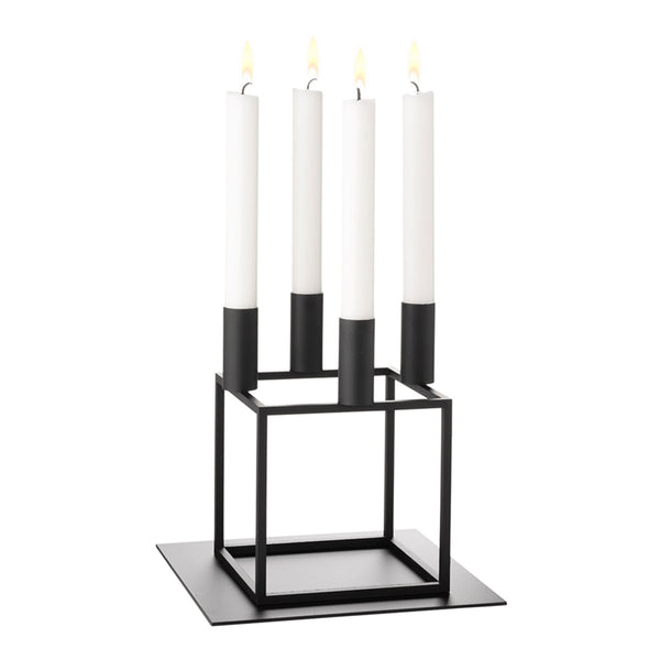 Minimalist black candle holder with four white candles and sleek geometric design. Perfect for modern decor.
