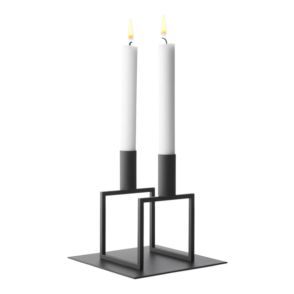 Minimalist black candle holder with two white candles, featuring modern geometric design and clean lines.
