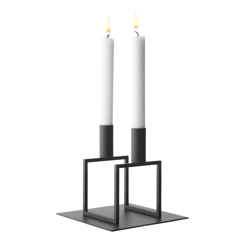 Minimalist black candle holder with two white candles, featuring modern geometric design and clean lines.