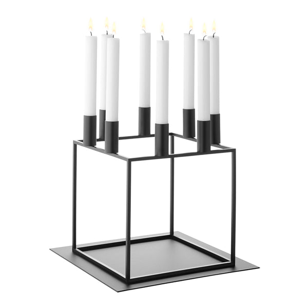 Black metal candle holder with geometric design, featuring six white candles with black bases.
