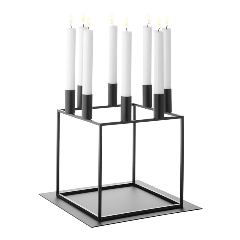 Black metal candle holder with geometric design, featuring six white candles with black bases.