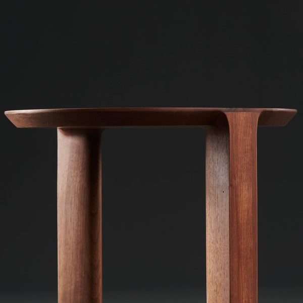 "Solid wood table with rich brown hues and smooth, minimalist design against a dark background."