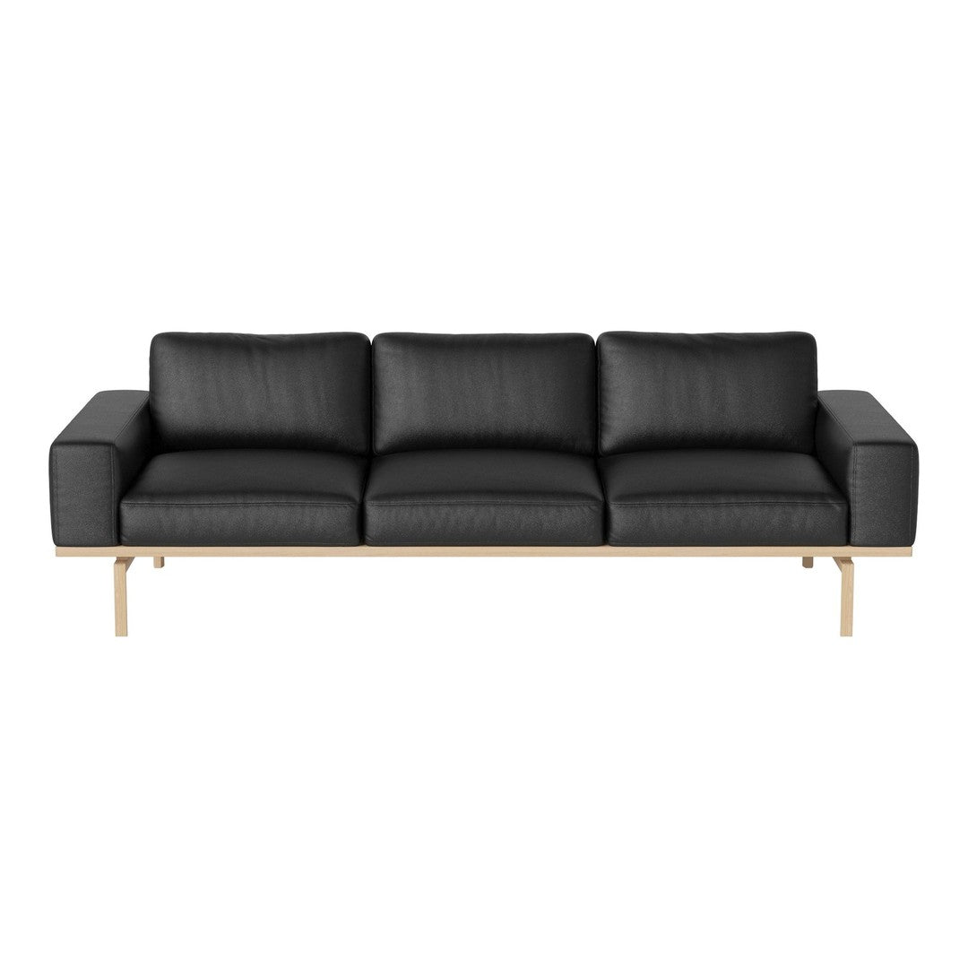 Modern black leather sofa with sleek lines and minimalistic design, featuring light wood legs for contrast.