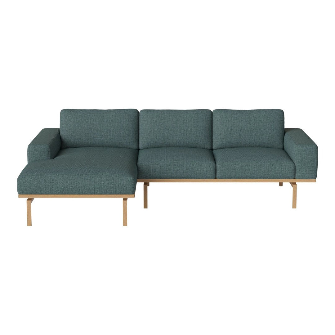 Teal upholstered sectional sofa with a modern design and light wood accents, featuring a smooth, textured fabric.