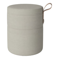 Light grey cylindrical storage ottoman with smooth fabric texture and tan leather handle. Modern minimalist design.