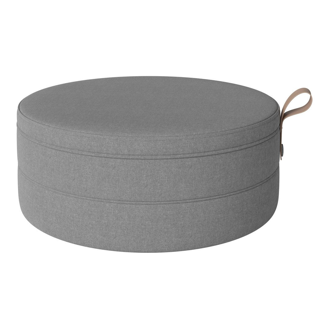 Round gray storage ottoman with a smooth texture and a stylish leather handle for easy carrying.