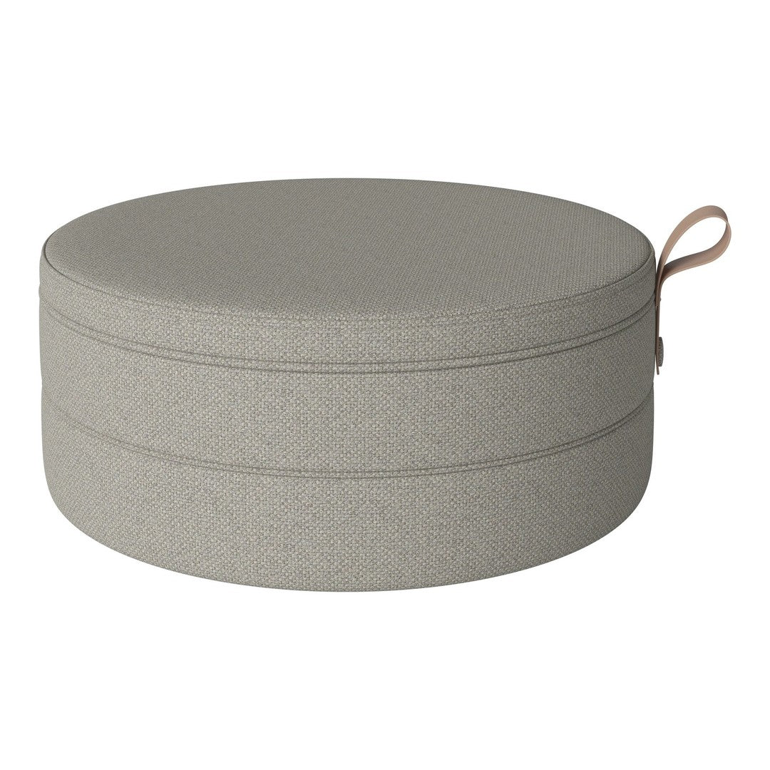 Round grey pouf with a smooth texture and subtle pattern, featuring a convenient leather handle for easy carrying.
