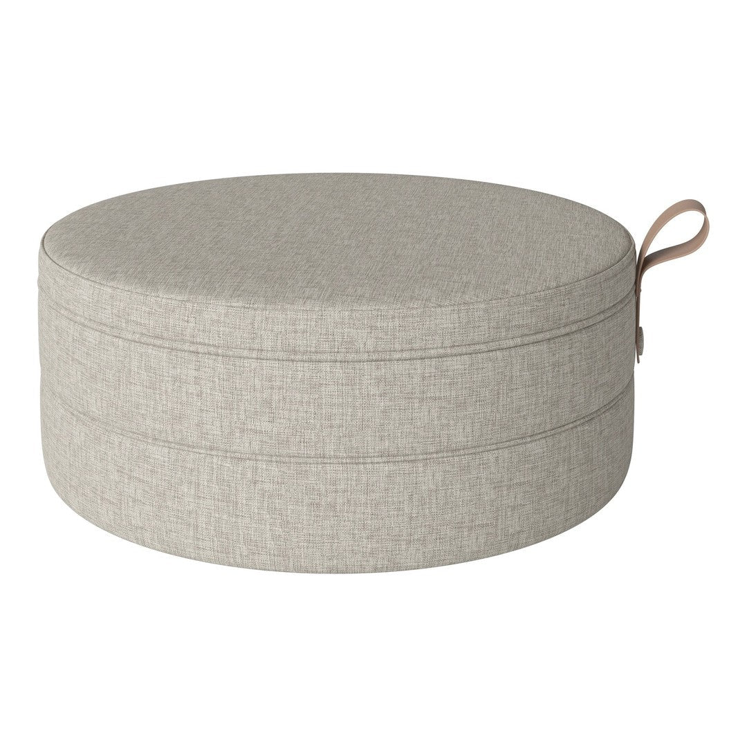 Round pouf in light gray fabric with a subtle textured pattern and a stylish handle. Perfect for any decor.