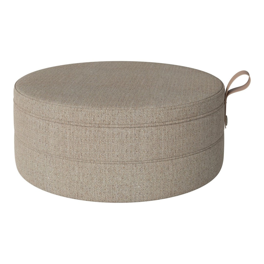 Round beige pouf with subtle textured pattern and practical carry handle. Ideal for stylish decor.