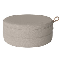 Round beige storage ottoman with a textured pattern and a convenient handle for easy carrying.