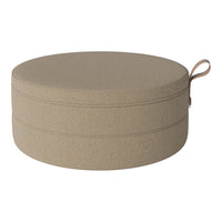Round storage ottoman in sandy beige fabric with a subtle textured pattern and a convenient handle.