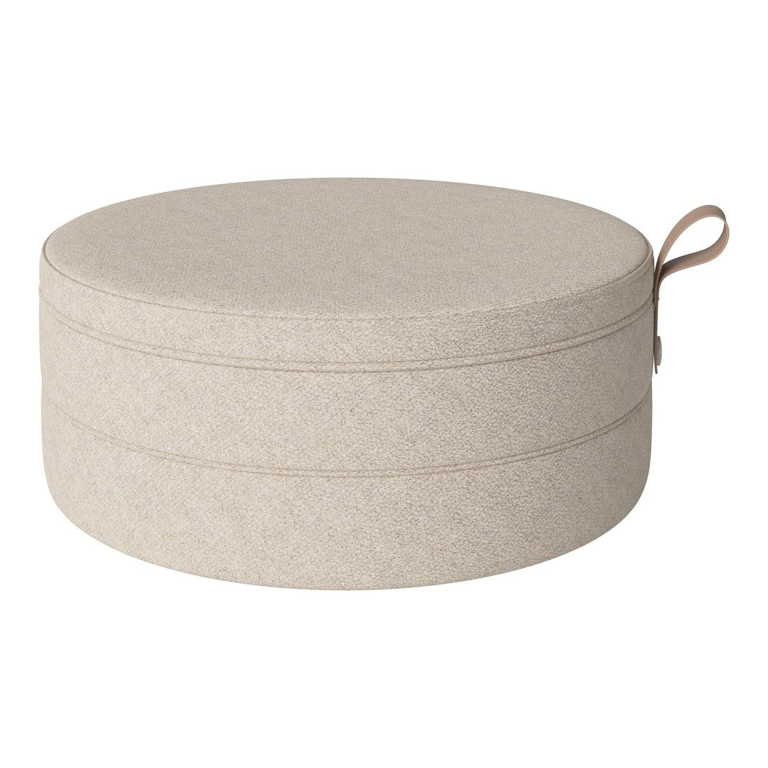 Round storage ottoman in soft beige fabric with subtle texture and a matching handle. Ideal for organizing stylishly.