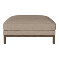 Beige upholstered ottoman with a smooth texture, featuring a dark wood frame for a modern touch.