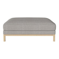 Gray upholstered ottoman with a subtle texture, resting on a light wood frame. Perfect for modern decor.
