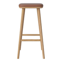 Wooden bar stool with a light oak finish and a warm brown leather seat cushion. Simple, modern design.
