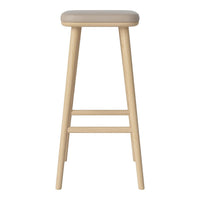 Light beige upholstered seat on a natural wooden bar stool with clean lines and a minimalist design.