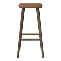 Brown leather seat on a dark wood stool, showcasing a minimalist design and natural textures. Ideal for modern decor.