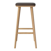 Brown upholstered stool with natural wood legs, featuring a simple, modern design. Ideal for minimalist decor.
