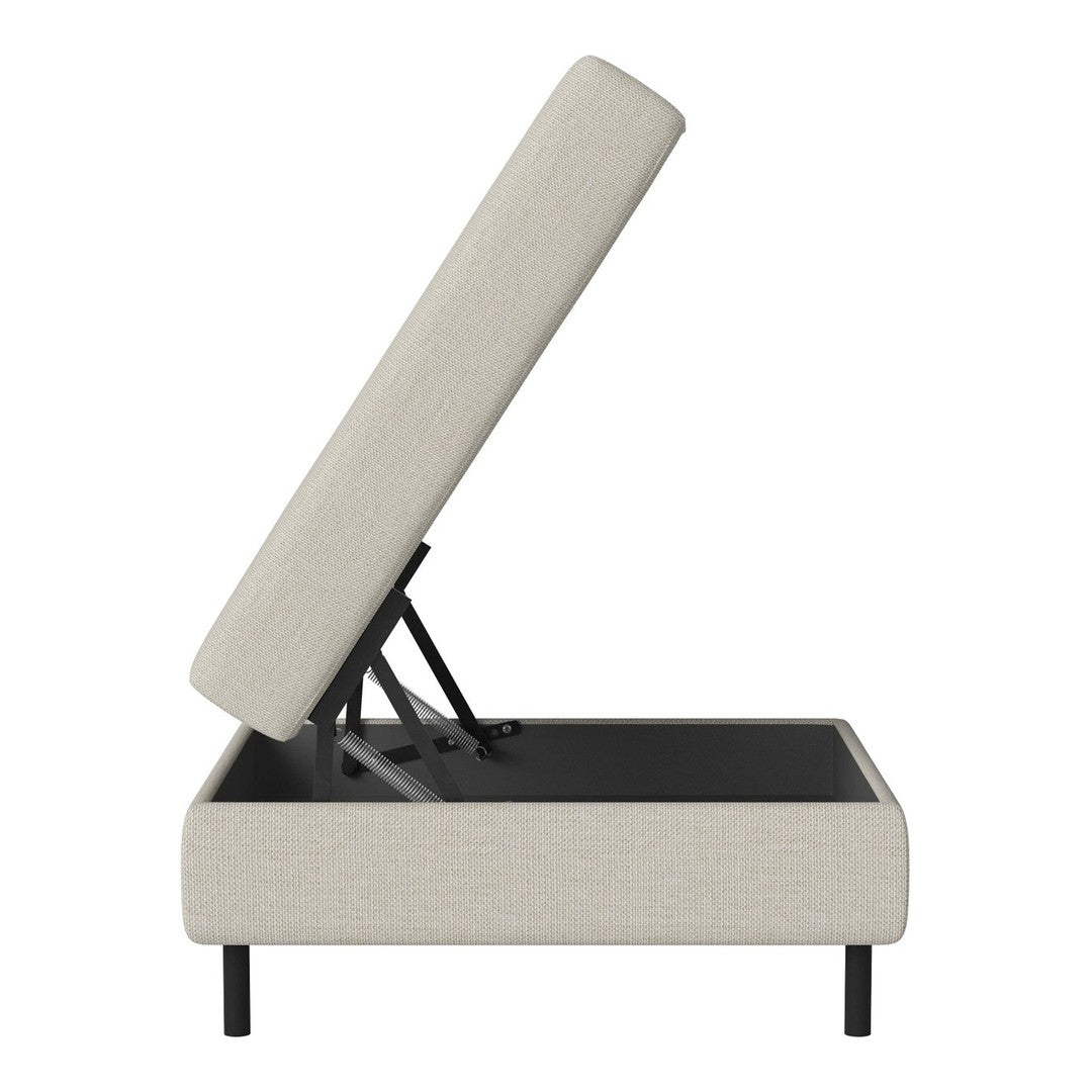 Light beige upholstered storage ottoman with sleek black legs and a simple, modern design.