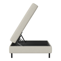 Beige upholstered ottoman with a hidden storage compartment and a sleek black base. Modern, minimalistic design.