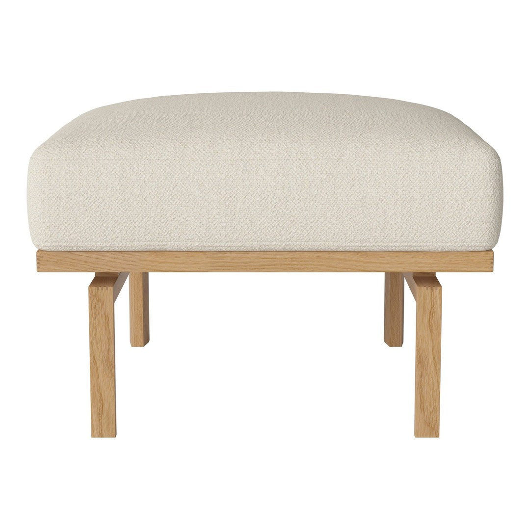 Beige upholstered ottoman with oak legs, featuring a smooth, neutral fabric texture. Ideal for modern decor.
