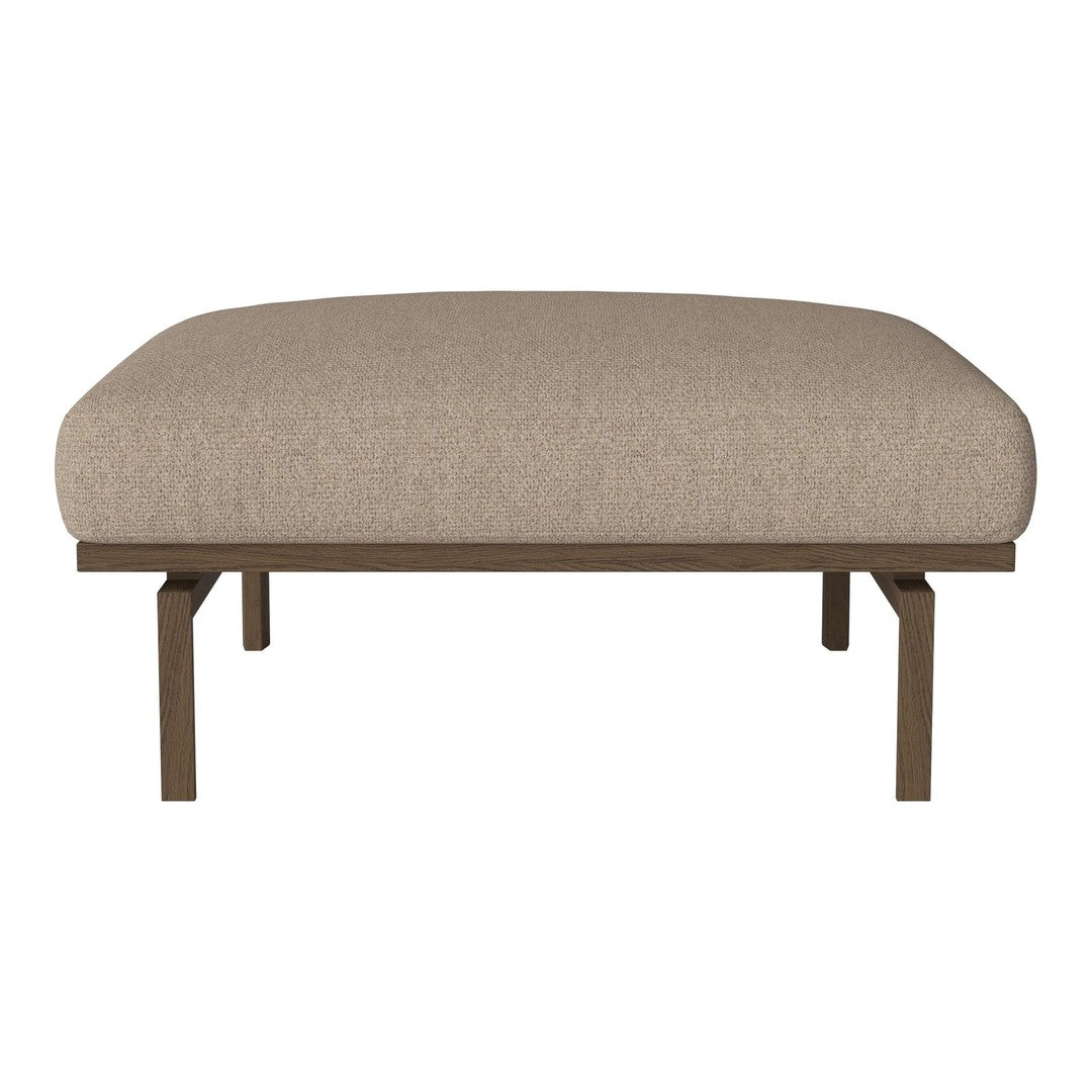 Beige upholstered ottoman with a smooth, rounded top and minimalist metal legs in a matte finish.