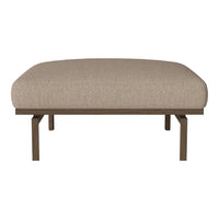 Beige upholstered ottoman with a smooth, rounded top and minimalist metal legs in a matte finish.