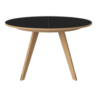 Round table with a sleek black top and natural wood legs, perfect for modern decor.