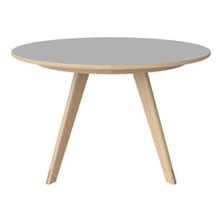 Round table with a smooth gray top and natural wood legs, showcasing a minimalist design and contemporary aesthetic.