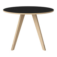 Round black table with natural wood legs, showcasing a minimalist design and contrasting colors. Perfect for modern decor.