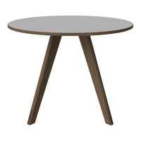 Round table with a smooth gray top and tapered wooden legs in a warm brown finish. Modern and minimalist design.
