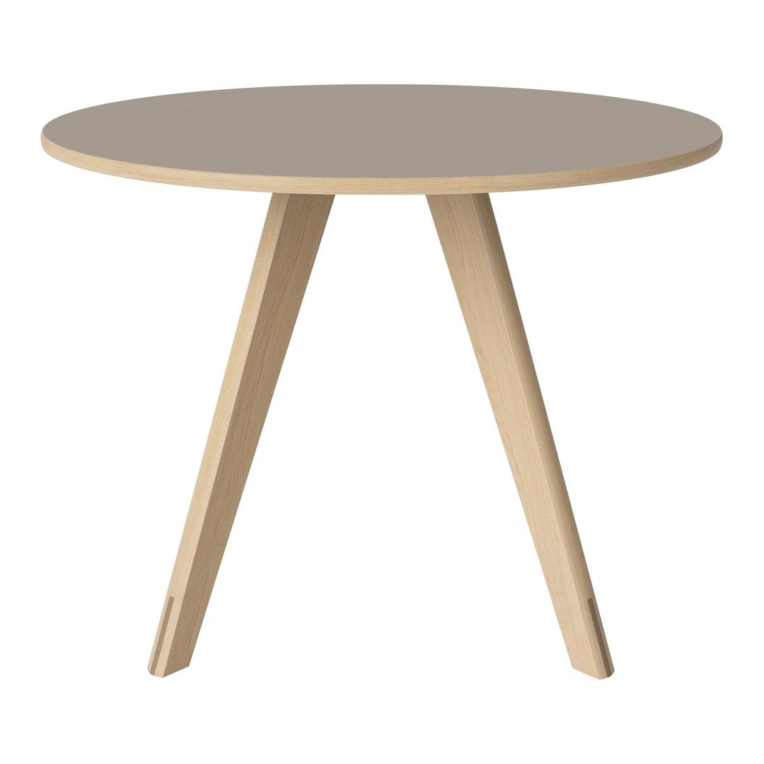 Round beige table with light wood legs, featuring a smooth, minimalist design. Perfect for modern decor.