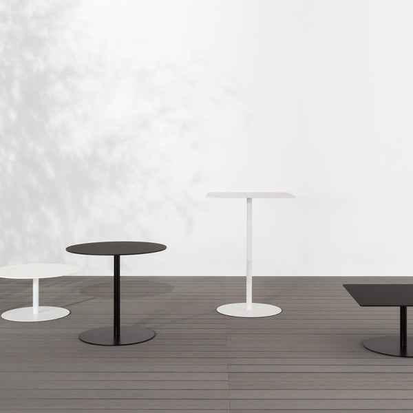 Four modern tables in black and white, featuring sleek circular and rectangular designs against a minimalist backdrop.