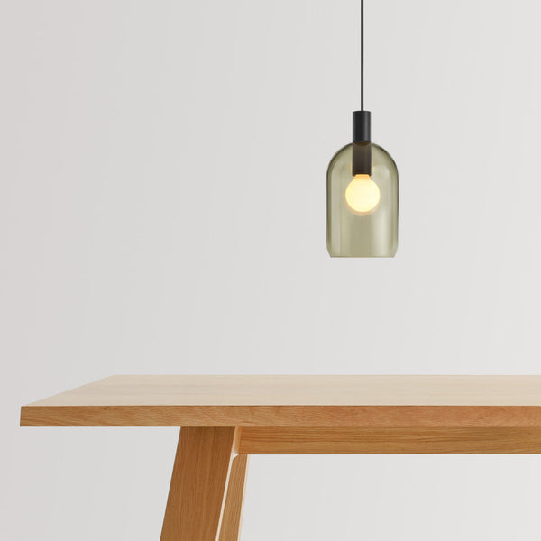 Green-tinted glass pendant light with a black fixture, showcasing a minimalist design against a neutral backdrop.