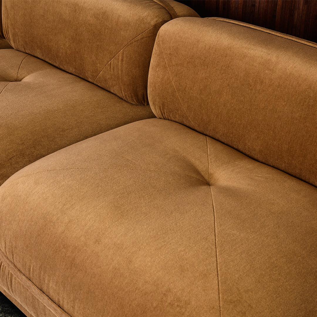 Brown suede sofa with tufted cushions, featuring a soft, textured finish.