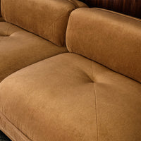 Brown suede sofa with tufted cushions, featuring a soft, textured finish.