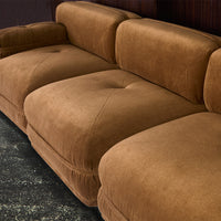 Brown velvet sectional sofa with a smooth texture and subtle tufted pattern. Ideal for modern living spaces.