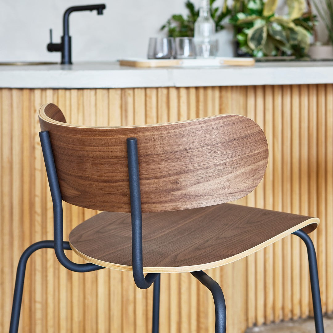 Modern chair featuring a warm walnut wood finish with sleek black metal accents and subtle curved patterns.