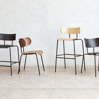 Four stylish chairs in black, brown, and natural wood tones with sleek metal frames, showcasing modern design and simplicity.