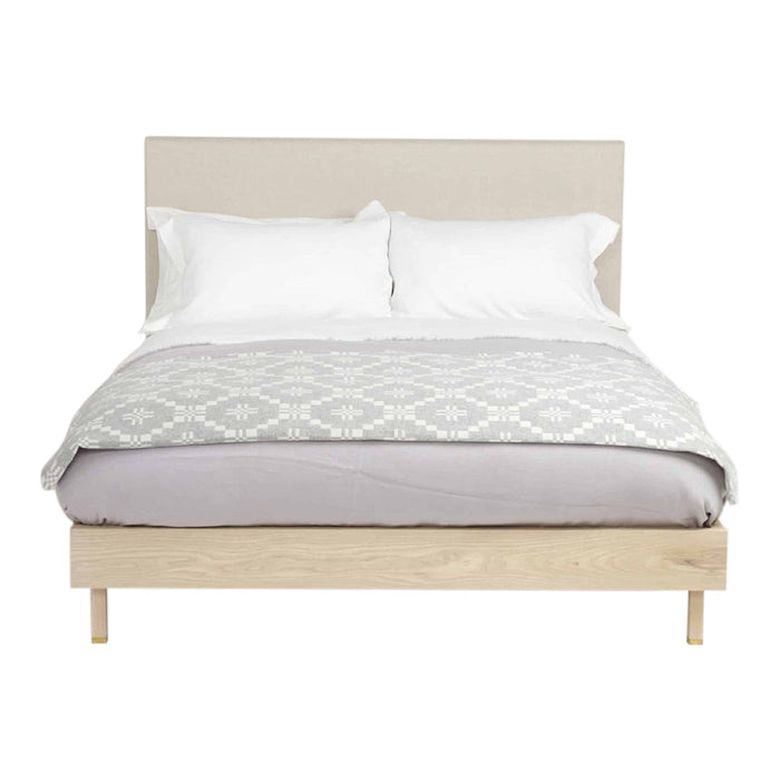 Soft gray and white geometric bedding atop a light wood frame, complemented by crisp white pillows.