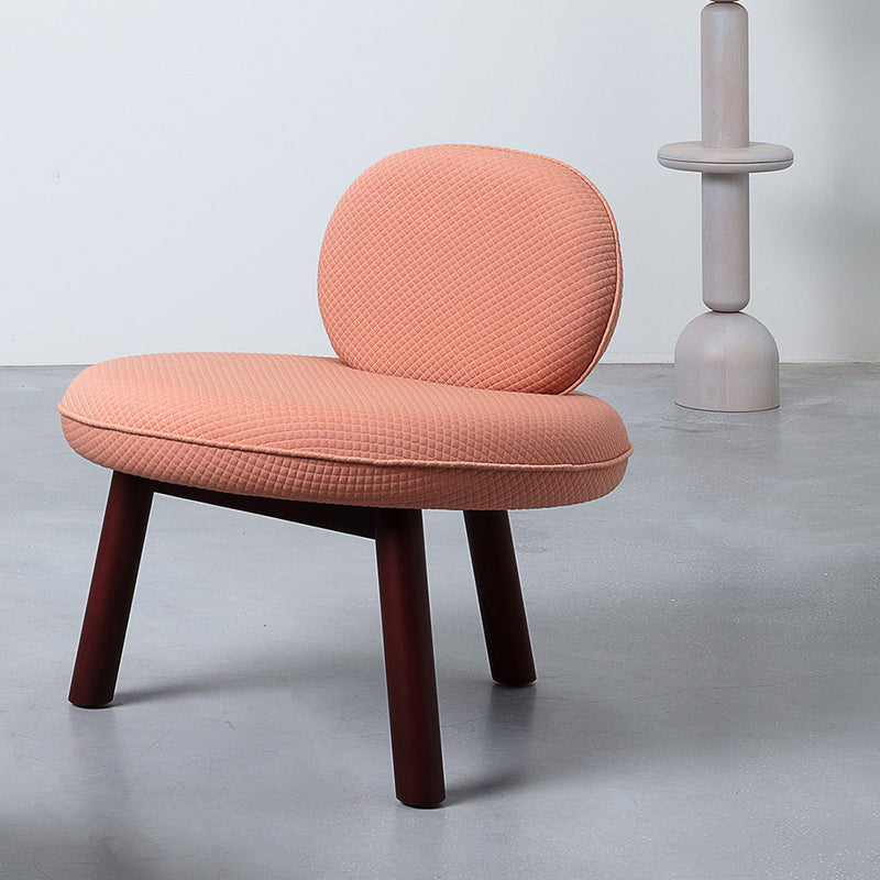 Peach quilted fabric chair with dark wooden legs, set against a minimalist gray background. Stylish and modern design.