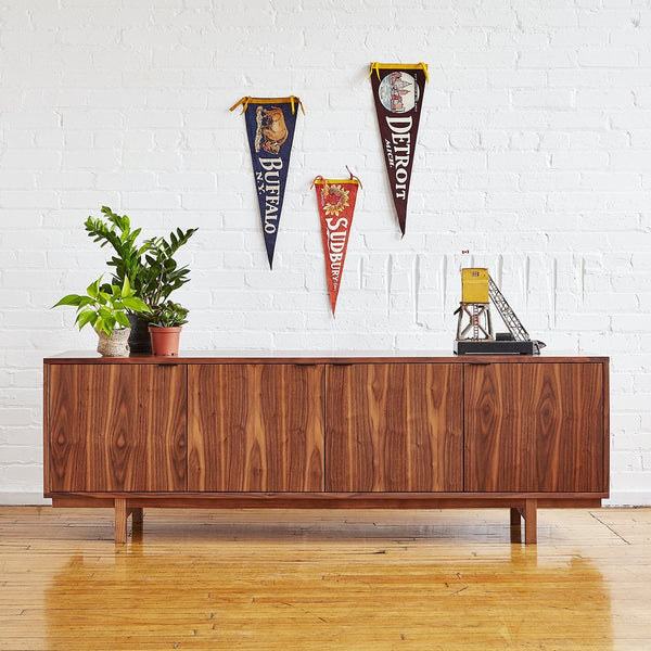 Wooden sideboard in rich brown tones, featuring a smooth finish. Wall decor includes colorful vintage pennants.