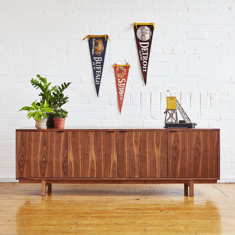 Wooden sideboard in rich brown tones, featuring a smooth finish. Wall decor includes colorful vintage pennants.